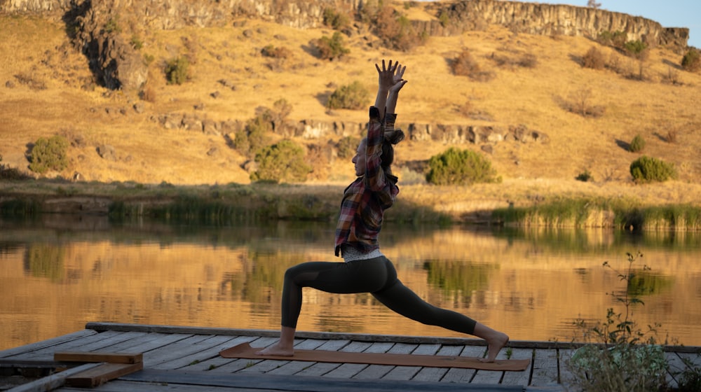 A person doing yoga by the river at sunrise